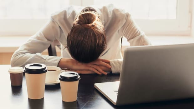Pessoa cansada, com a cabeça apoiada na mesa de trabalho