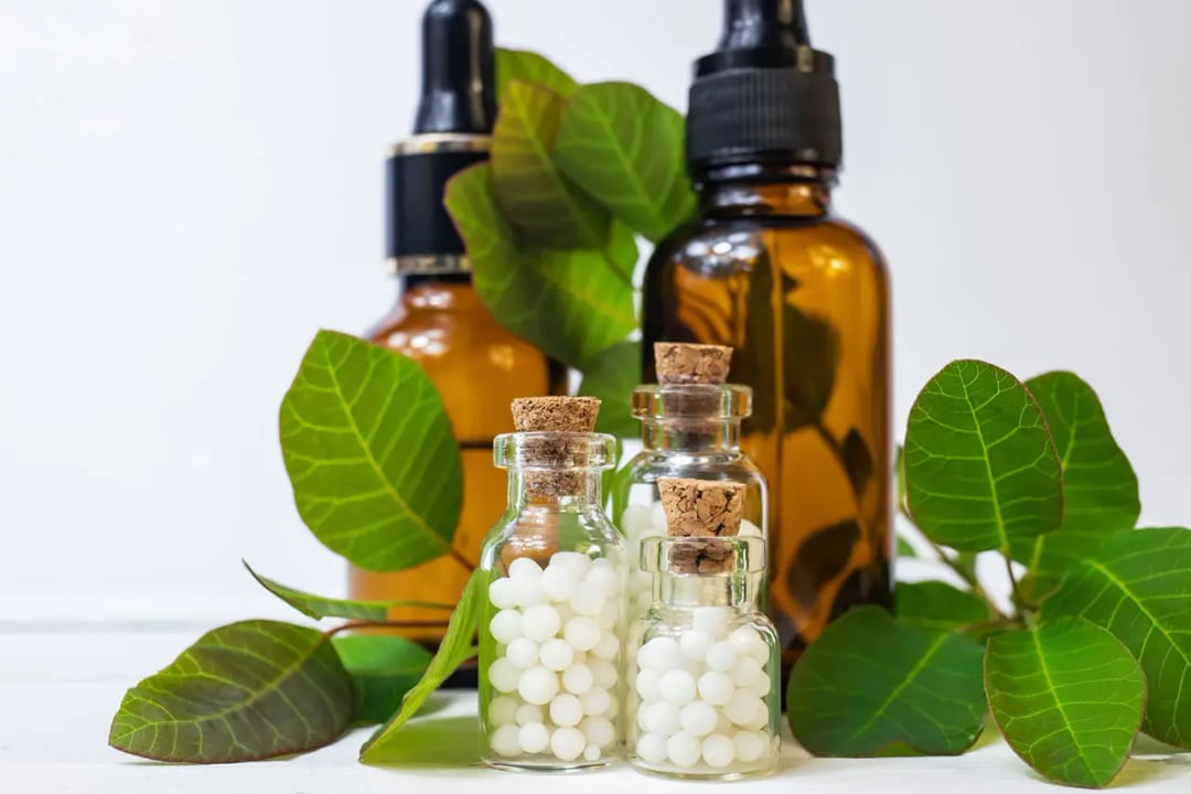 Frascos de vidro com glóbulos homeopáticos entre folhas verdes