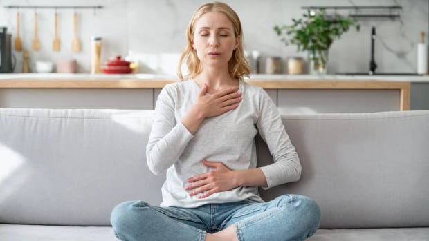 Pessoa sentada, com as mãos sobre o peito e o abdômen, respirando